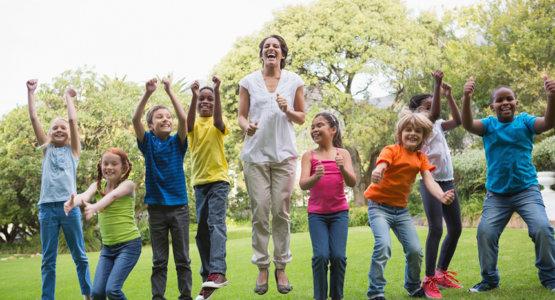 Teacher outside jumping with students