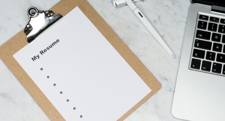 blank resume with bullet points on clipboard next to computer