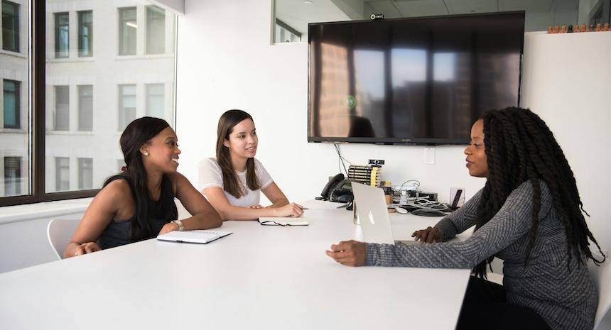 job interview with one person facing two other people across a table in an office meeting room