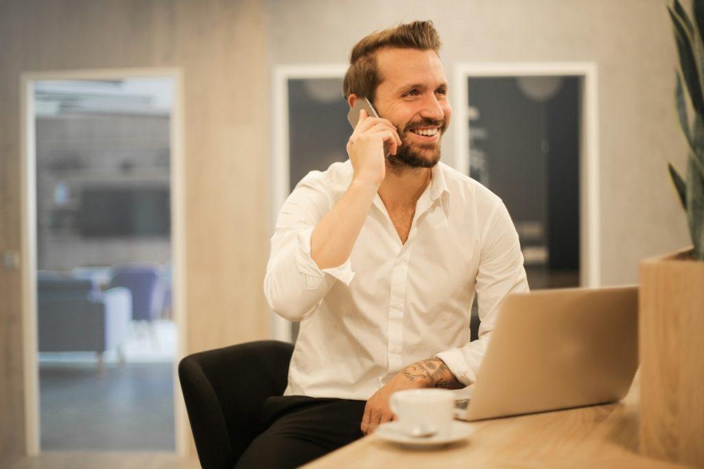 person in white collared shirt on phone at computer