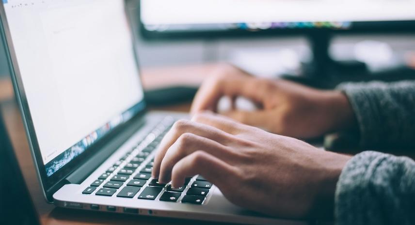 picture of hands typing on a laptop with word doc open on screen