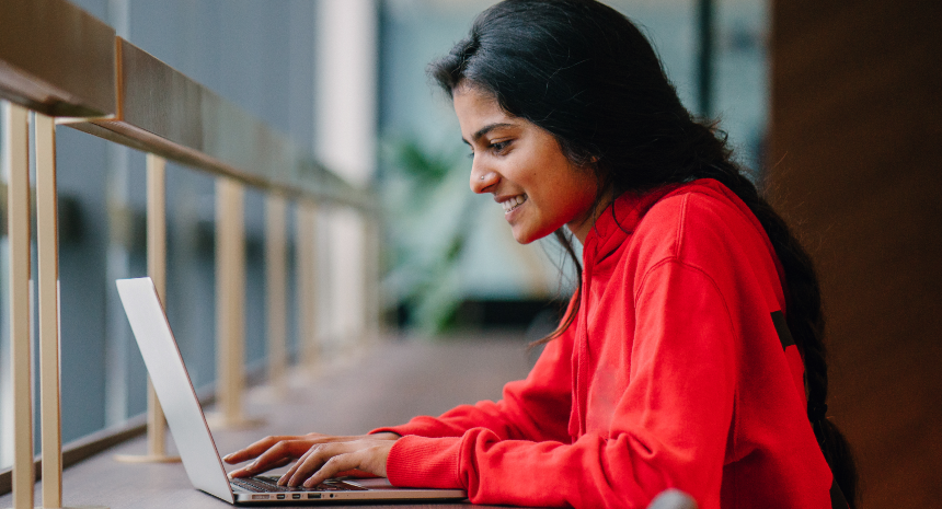 Young woman writing a resume on laptop to showcase college internships.
