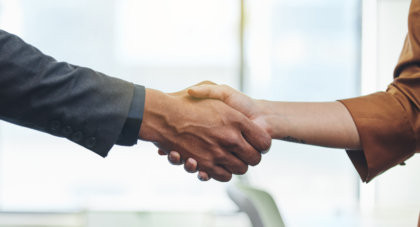 Coworkers shaking hands indicating a promotion at work.