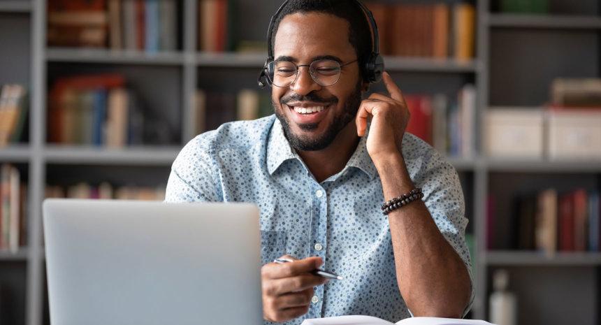 A man smiling looking at his laptop screen